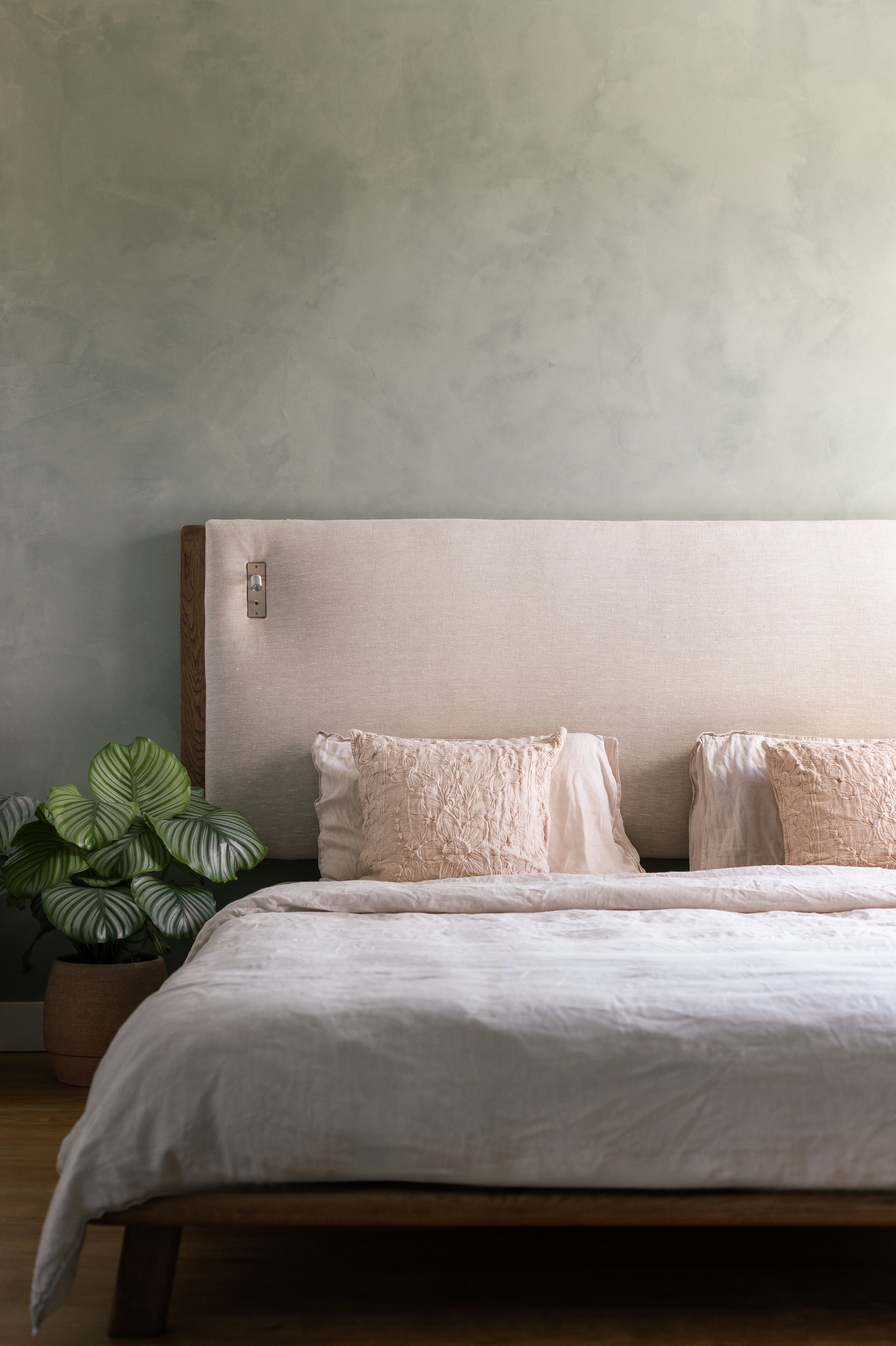 Chambre parentale, tête de lit en lin, mur à la chaux verte et plante